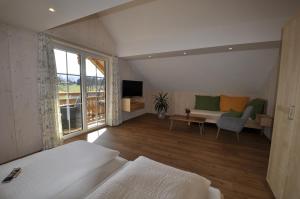 a hotel room with a bed and a couch and a tv at Ferienwohnungen Holzidylle in St. Wolfgang