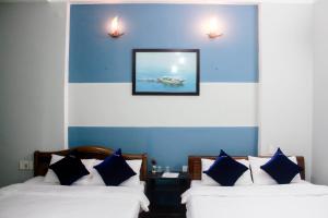 two beds in a room with a picture on the wall at Hana Homestay Danang in Da Nang