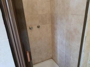 y baño con ducha y azulejos beige. en Miami guest house en Vereeniging