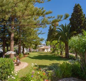 um jardim com árvores e uma casa ao fundo em Quinta Paraiso da Mia - 1 Bedroom Apartment na Praia da Luz
