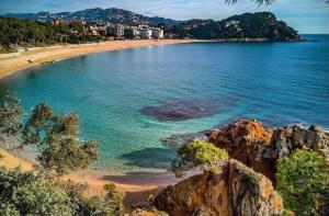 a view of a beach with rocks and the ocean at SeaHomes Vacations, FENALS BEACH&CHIC, pk, top apartment full equipped in Lloret de Mar