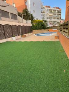 a yard of green grass next to a pool at SeaHomes Vacations, FENALS BEACH&CHIC, pk, top apartment full equipped in Lloret de Mar