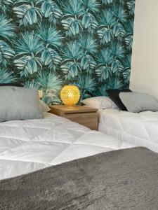 a bedroom with two beds and a wallpaper with plants at SeaHomes Vacations, FENALS BEACH&CHIC, pk, top apartment full equipped in Lloret de Mar