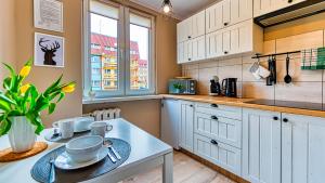 a kitchen with white cabinets and a table at Apartament Emili - 5D Apartamenty in Szklarska Poręba