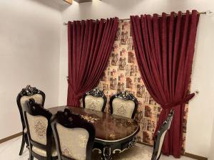 ラホールにあるRoyal Three-Bedroom Villa Dha Phase 6 Lahoreの赤いカーテン、テーブルと椅子付きのダイニングルーム
