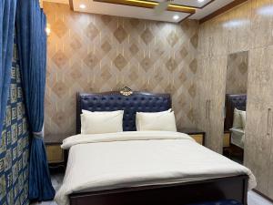 ラホールにあるRoyal Three-Bedroom Villa Dha Phase 6 Lahoreのベッドルーム1室(大型ベッド1台、青いヘッドボード付)