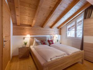 Cette chambre comprend un grand lit et un plafond en bois. dans l'établissement Alpen Glück Schlössl Unterm Rain, à Kirchberg in Tirol
