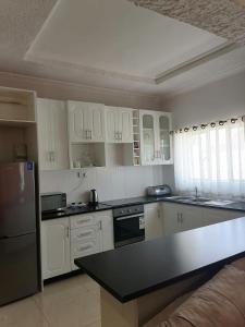 uma cozinha com armários brancos e um balcão preto em 848 Guest House em Victoria Falls