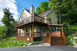 a large house with a large deck on a hill at Le Très-Chic - SPA, billard, souvenirs in Baie-Saint-Paul