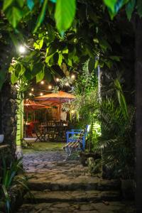 an outdoor patio with a table and chairs and trees at Pousada Bartholomeu in Paraty