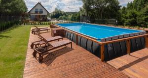 a pool on a deck with two chairs and a table at Water House - Domy Mazur in Ełk
