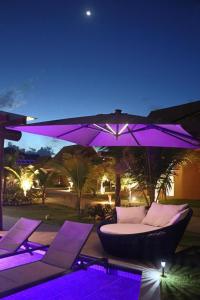 a purple lighting up a patio with a couch and an umbrella at Warung Praia Dos Carneiros in Praia dos Carneiros