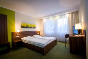 a bedroom with a bed and a desk and a television at Hotel Europa in Elblag