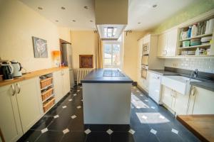 uma grande cozinha com armários brancos e um piso preto e branco em Le Richmond em Godinne