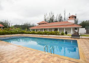 a swimming pool in front of a house at SR Jungle Resort in Coimbatore