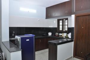 a kitchen with wooden cabinets and a blue refrigerator at Maanas Homestay in Tirupati