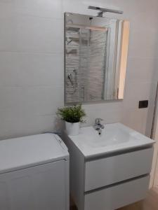 biała łazienka z umywalką i lustrem w obiekcie Casa Mare Ludovica w mieście Vasto