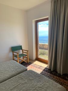 a room with two beds and a window with a chair at Bela Vista in Penhas da Saúde