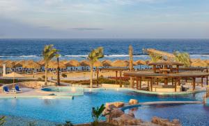 a resort with two pools and umbrellas and the ocean at Lazuli Hotel, Marsa Alam in Quseir