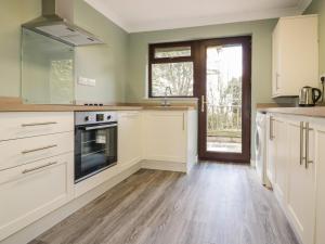 a kitchen with white cabinets and a wooden floor at Three Jays in Looe