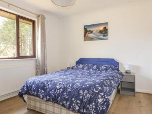 a bedroom with a blue bed and a window at Three Jays in Looe