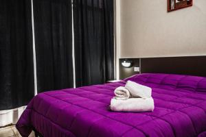 a purple bed with towels on top of it at Hotel Italia in Villa Carlos Paz +25 photos