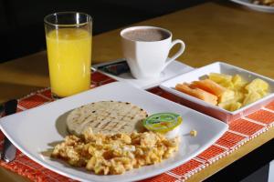 a plate of breakfast food with a glass of orange juice at Hotel Santa Maria in Popayan