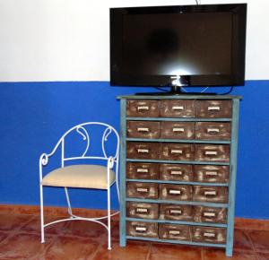 una silla sentada junto a un tocador con un televisor. en Casas Rurales Lagunas de Ruidera - Piscina, en Ossa de Montiel
