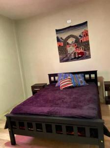 Cette chambre comprend un lit avec des draps violets et une peinture murale. dans l'établissement MORTERO II, à Cafayate