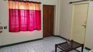 Cette chambre dispose d'un rideau rouge et d'une porte en bois. dans l'établissement Ahobilaa Homestay, à Tiruchirappalli