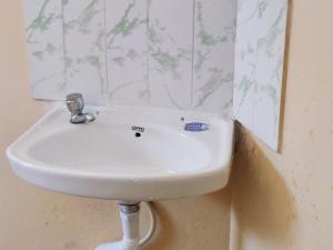 La salle de bains est pourvue d'un lavabo blanc et d'un miroir. dans l'établissement Ahobilaa Homestay, à Tiruchirappalli