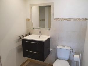 Un baño con inodoro, lavabo y espejo. en studio vllage, en Entrecasteaux