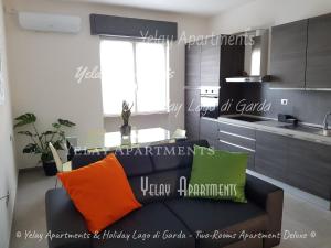 sala de estar con sofá y almohadas de color naranja y verde. en Yelay Apartments & Holiday Lago di Garda, en Raffa