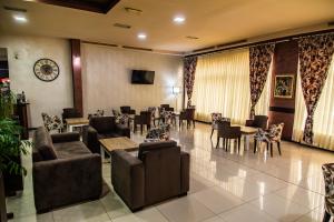 a lobby with chairs and tables and a clock on the wall at Hotel Albo in Bor