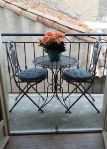 2 sillas y una mesa con un jarrón de flores en el balcón en Lourecantou, en Saint-Thibéry