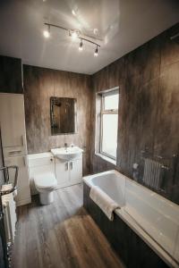 a bathroom with a tub and a toilet and a sink at PARKER St by Prestige Properties SA in Barrow in Furness