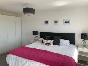 a bedroom with a large bed with a pink blanket at The Bungalows Guesthouse in Threlkeld