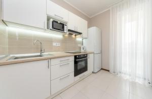 a white kitchen with a sink and a microwave at Стильна та затишна квартира у новому будинку на Оболоні, 5 поверх in Kyiv +6 photos