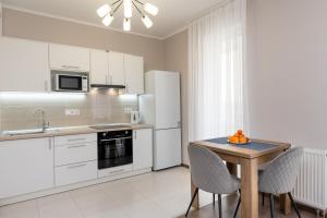 a kitchen with white appliances and a table with chairs at Стильна та затишна квартира у новому будинку на Оболоні, 5 поверх in Kyiv