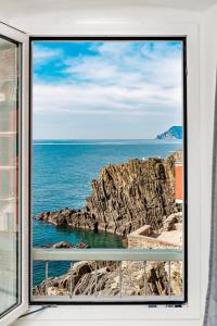 a window view of the ocean and rocks at il Mare di Ada:seaside apartament in Riomaggiore in Riomaggiore