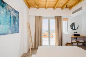 a bedroom with a bed and a large window at Blue Orchid Villa Mykonos in Kalafatis