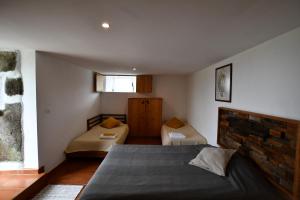 a bedroom with two beds and a brick wall at Caldeira Guesthouse in Fajã da Caldeira de Santo Cristo