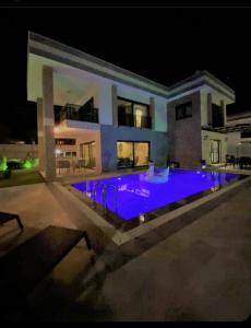 a large swimming pool in front of a house at night at magnifique villa avec piscine prive kusadasi in Kuşadası