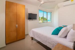 a bedroom with a bed and a cabinet and a television at Magico Apartamento Frente al Mar 2 Habitaciones B22B in Coveñitas