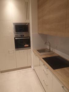 a kitchen with white cabinets and a sink at Gwiazda Bemowa in Warsaw