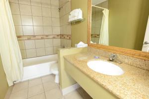 a bathroom with a sink and a toilet and a mirror at Burlington Inn in Burlington