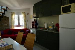 a kitchen with black cabinets and a red couch at Apartamentos Fornells in Castelló d'Empúries