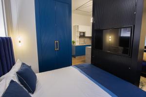 1 dormitorio con 1 cama y TV y cocina en LIT Apartments, en Tirana