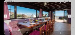 Un comedor con mesa y sillas y una gran ventana. en Villa Calma, en Yaiza