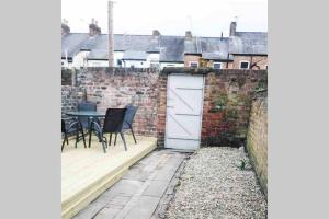 a patio with a table and chairs and a brick wall at The Terrace Chester, modern 3 bed house in Chester